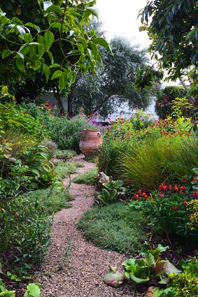 Gravel paths wind through perennial borders and lead to a sitting spot under the olive tree overlooking the garden, which is spilling with colour.
 

