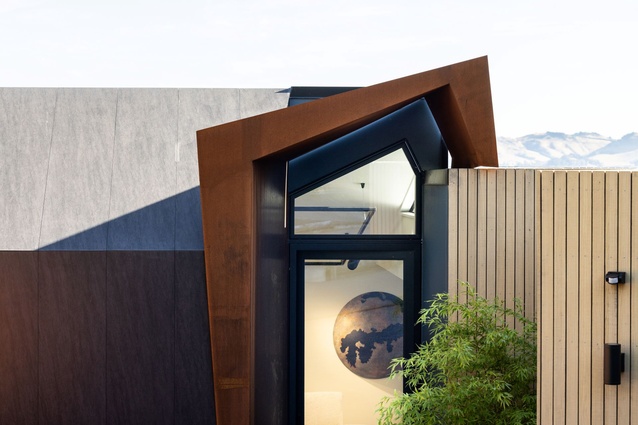 The entrance is sculptural, with angles that are juxtaposed against the softness of the landscape.