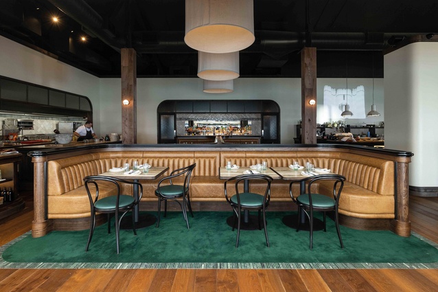 Elegant tan-leather booth seating is flanked by an open kitchen on one side and casual dining on the other.