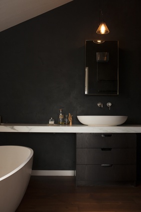 The bathroom is clad in black and is softened with marble finishings. 