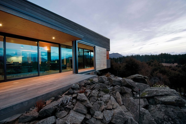 The covered timber deck on the Kānuka Rise house has direct connection to the rock outcrop.